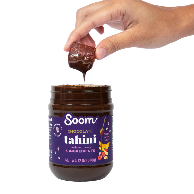 Brownie tahini bite dipped into jar of Soom Chocolate Tahini